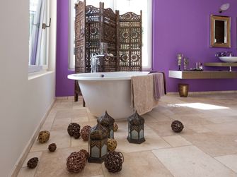 Fliserne Travertine Light i et badeværelse med fritstående badekar og lilla væg i baggrunden