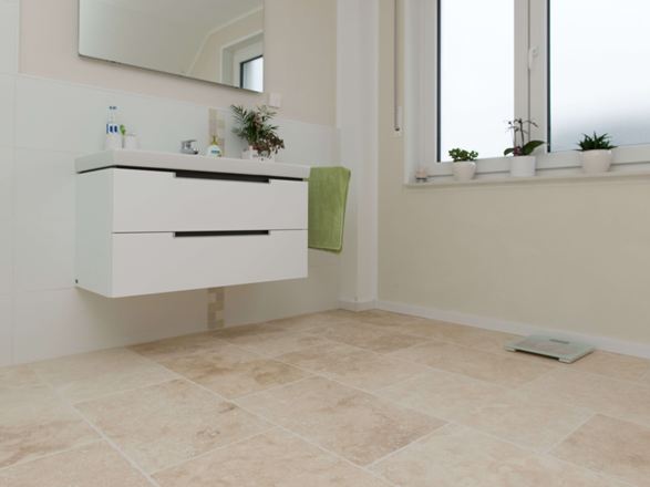 Light travertinfliser i moderne badeværelse med hvide møbler