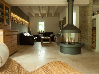 Stue med fritstående pejs og siddegruppe på Light travertinfliser, en kurvelænestol i forgrunden