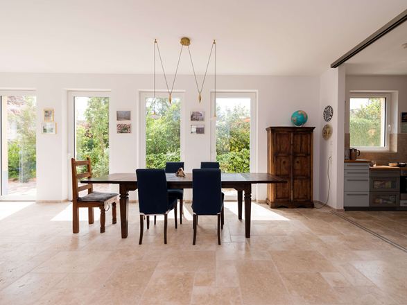 Lys spiseplads med træmøbler og beige travertinfliser som gulvbelægning