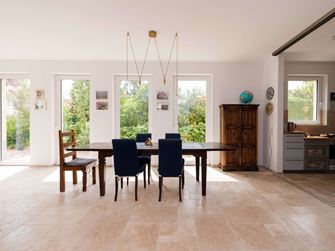Lys spiseplads med træmøbler og beige travertinfliser som gulvbelægning