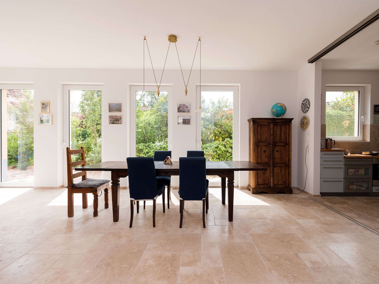 Lys spiseplads med træmøbler og beige travertinfliser som gulvbelægning