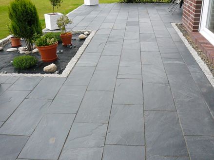 Terrasse med potteplanter og Black Rustic skifer som gulvbelægning, til højre kan man se en muret husmur