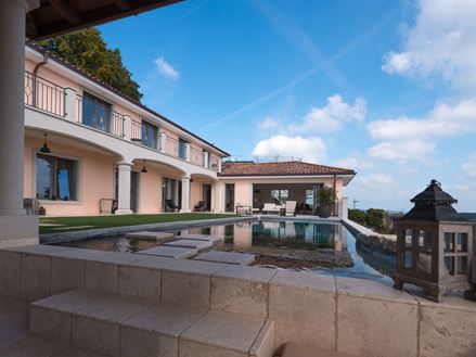 Udsigt over poolen og huset med Light travertinplade i en blød beige farve