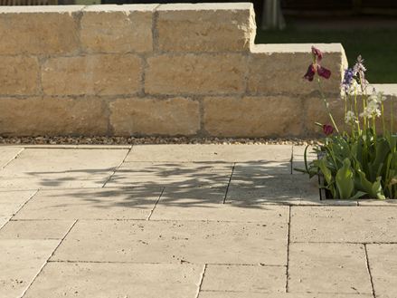 Medium Select travertinplade med naturstensvæg og blomster i baggrunden