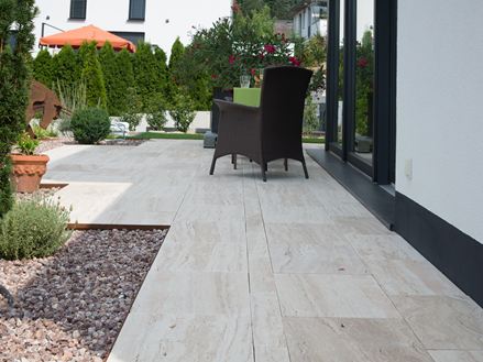 Moderne terrasse med Natura træ-effekt travertinplader og mørke kurvemøbler