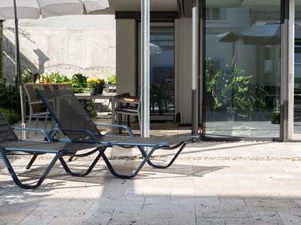 Stilfuld gårdhave med travertin og smukt solbadningsområde