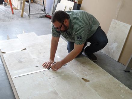 Adalbert Lange markerer ujævnhederne i fliserne, så de derefter kan skæres til plader