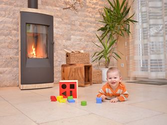 Baby leger på et naturstensgulv foran en pejs