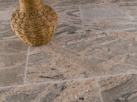 Juparana Colombo fliser i rødgrå med en brun dekorativ vase