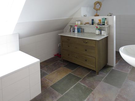 Farverig skifer på badeværelset supplerer det hvide interiør på vidunderlig vis