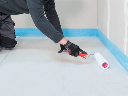 Flisemurer påfører primeren med en rulle