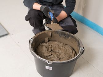 Flisemurer foran en spand med naturstensklæber