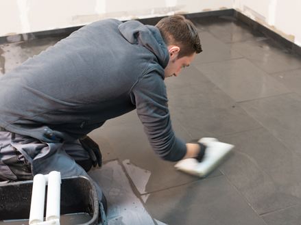 Flisebelæggeren renser gulvet