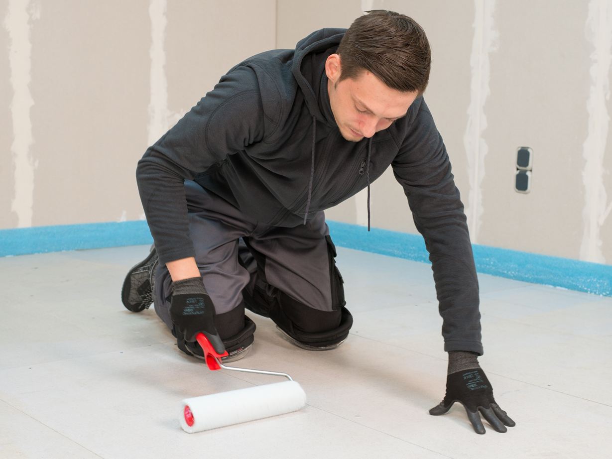 Flisemurer påfører primeren med en rulle