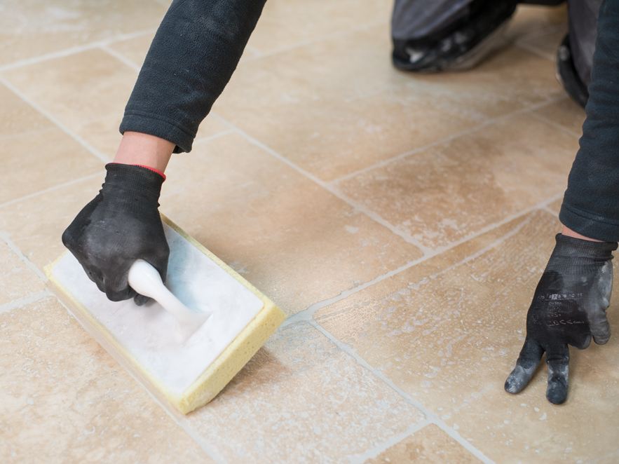 Flisebelæggeren renser travertingulvet efter lægning