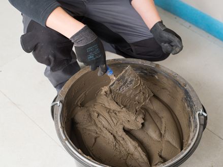 Flisemurer rører i en spand med naturstensmørtel