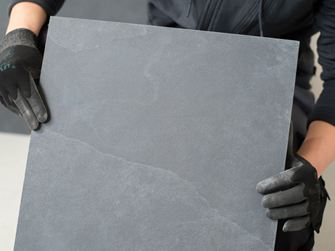 Flisemageren holder en skiferflise op til kameraet