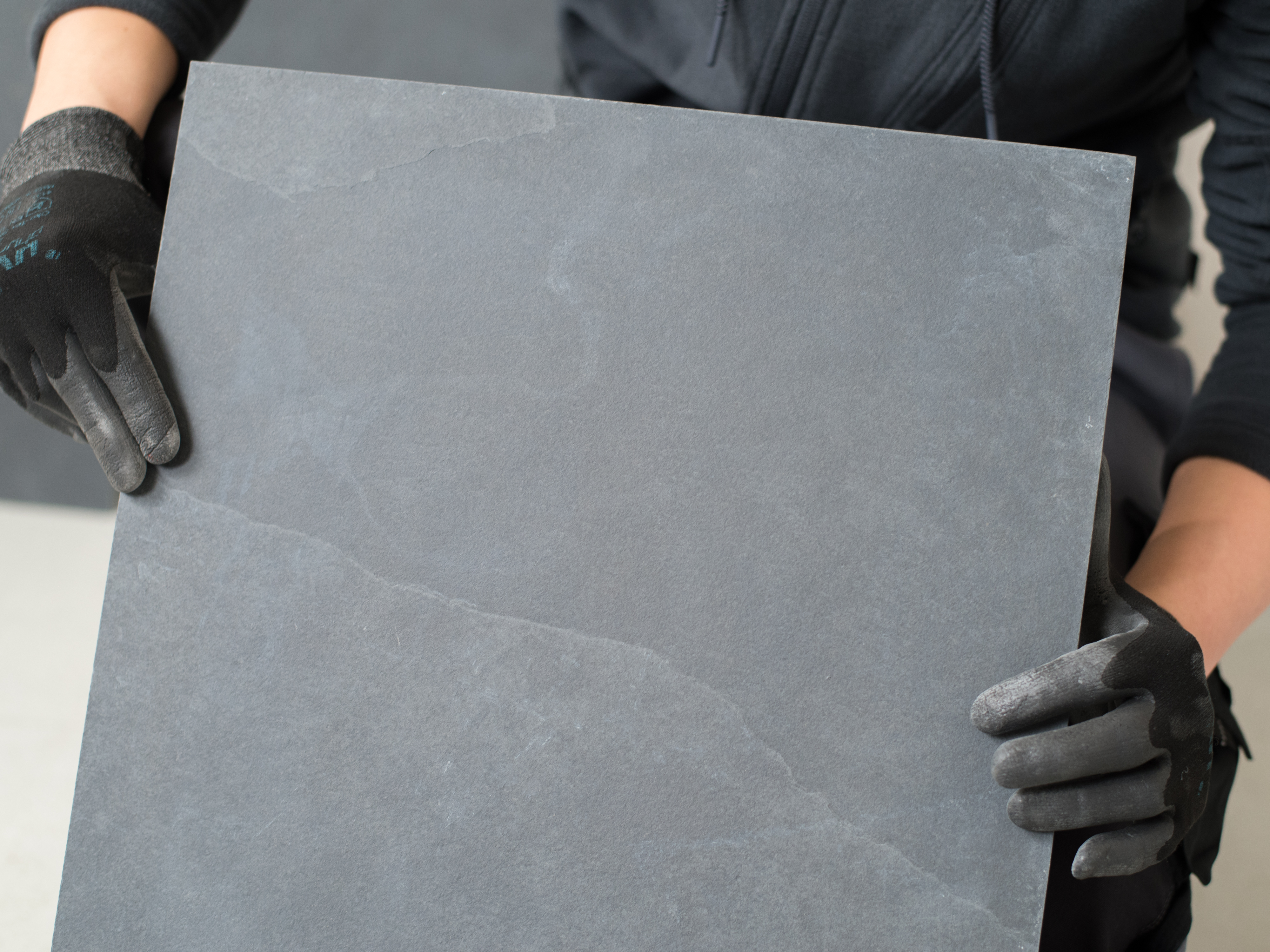 Flisemageren holder en skiferflise op til kameraet