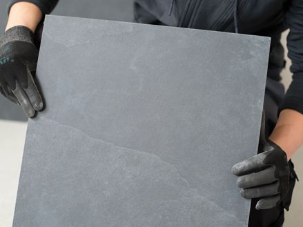 Flisemageren holder en skiferflise op til kameraet