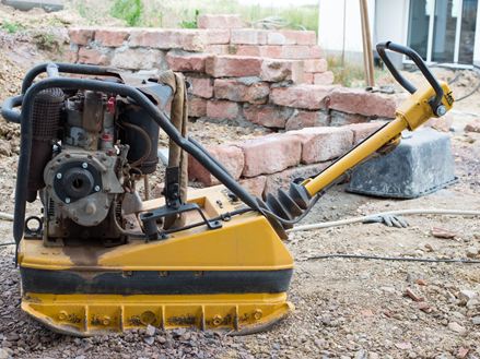Foto af en pladevibrator på en byggeplads, der bruges til at komprimere det ballastholdige bærelag