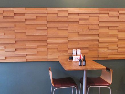 Et bord med to stole foran en grå væg med brune træpaneler i en bistro.