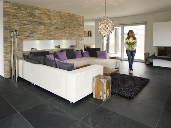 Moderne stue med naturstenspaneler på væggen, skiferfliser som gulvbelægning og en hvid sofa