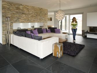 Moderne stue med naturstenspaneler på væggen, skiferfliser som gulvbelægning og en hvid sofa