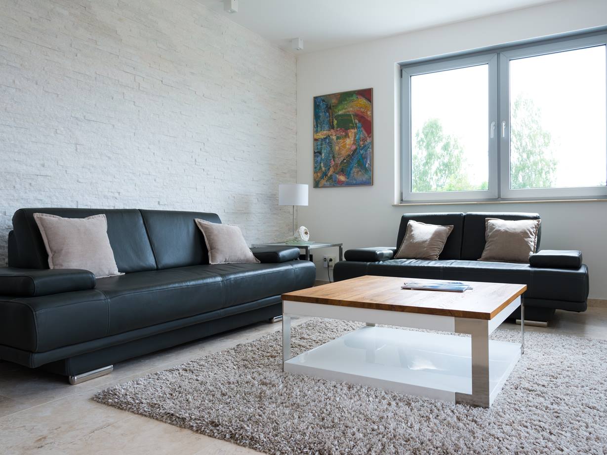 Stue med naturstenspaneler på væggen og en sort sofa