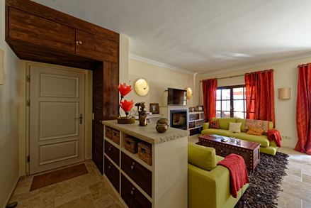 Stue i middelhavsstil med grøn sofa og røde gardiner