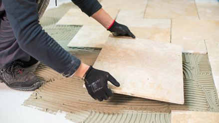 En flisemurer lægger en travertinflise
